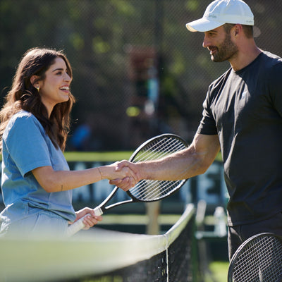 guy and girl shaking hands at tennis court net