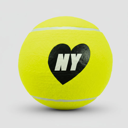 Yellow tennis ball with a black heart and 'NY' text on a light gray background