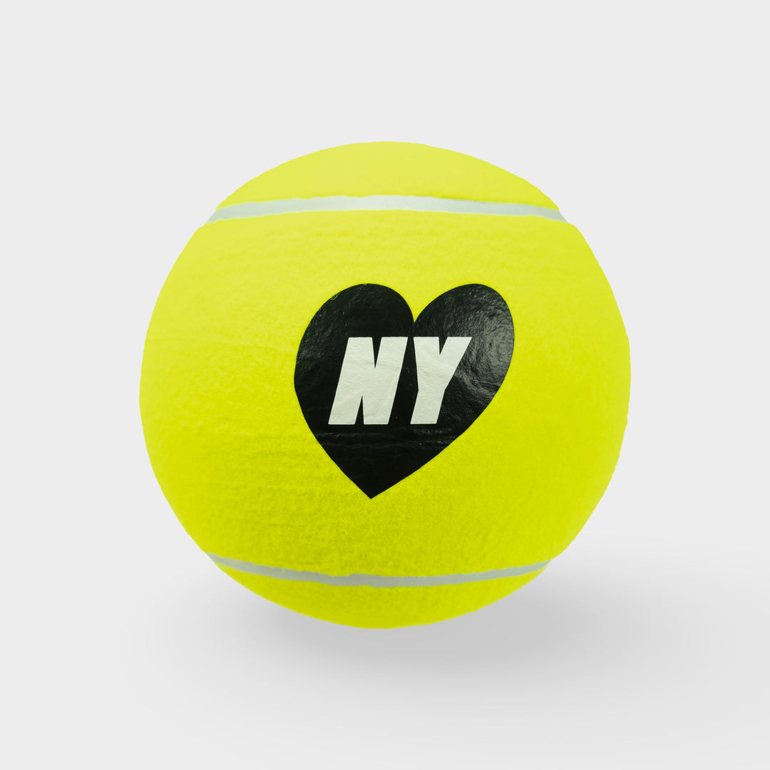 Yellow tennis ball with a black heart and 'NY' text on a light gray background