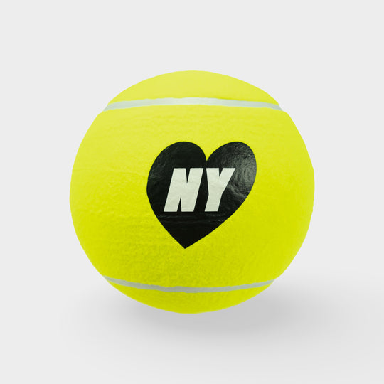 Yellow tennis ball with a black heart and 'NY' text on a light gray background